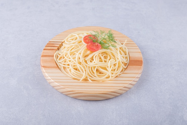 Leckere gekochte Spaghetti mit Tomaten auf Holzplatte.