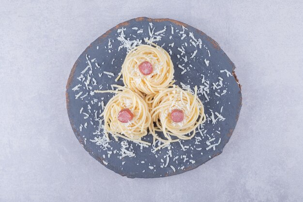 Leckere gekochte Spaghetti mit Würstchen auf Holzstück.