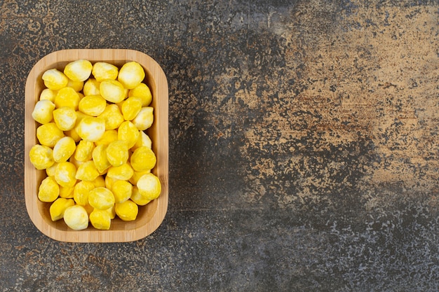 Kostenloses Foto leckere gelbe bonbons auf holzteller.