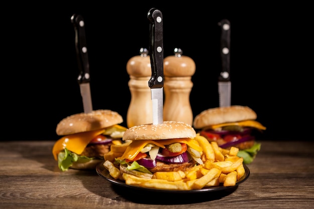 Leckere Gourmet-Köstliche Burger auf schwarzem Teller neben Pommes. Fastfood. Ungesunder Snack