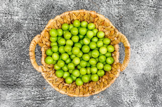 Leckere Greengages in einem Weidenkorb auf Grunge-Oberfläche, Draufsicht.