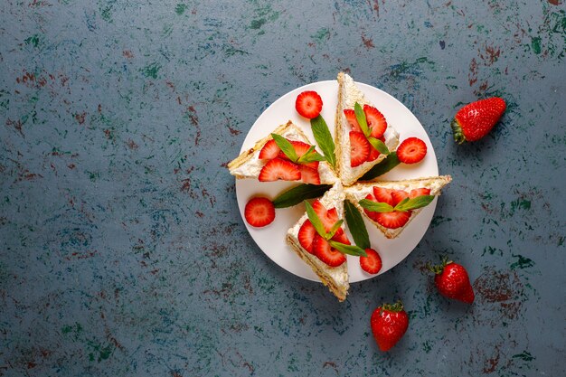 Leckere hausgemachte Erdbeerkuchenscheiben mit Sahne und frischen Erdbeeren, Draufsicht