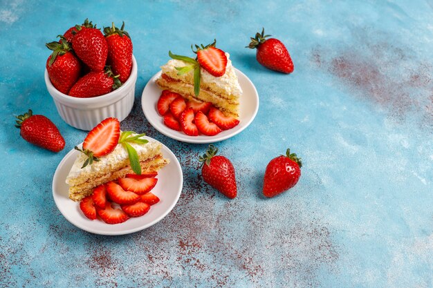 Leckere hausgemachte Erdbeerkuchenscheiben mit Sahne und frischen Erdbeeren, Draufsicht