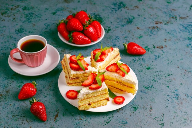 Leckere hausgemachte Erdbeerkuchenscheiben mit Sahne und frischen Erdbeeren