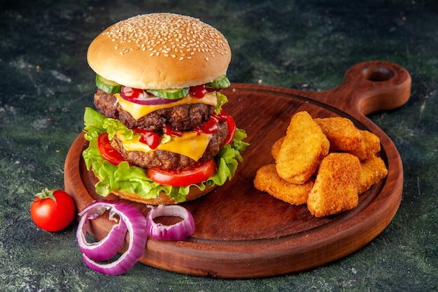 Leckere hausgemachte Sandwich-Tomaten Pfeffer auf Holzbrett Zwiebeln Tomate mit Stiel Hühnernuggets auf dunkler Farbe Oberfläche