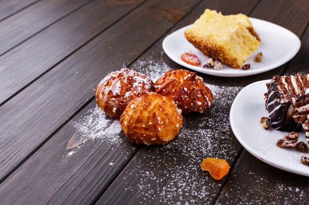 Leckere Kekse, Käsekuchen und Schokoladenkuchen mit Zuckerpulver bedeckt