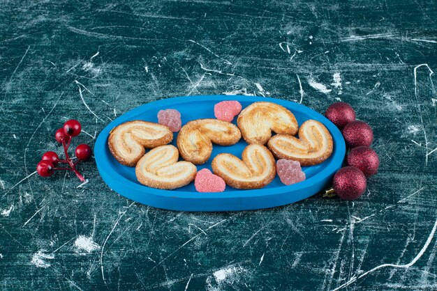 Leckere Kekse mit Zuckergelee-Süßigkeiten auf einem blauen Brett. Foto in hoher Qualität