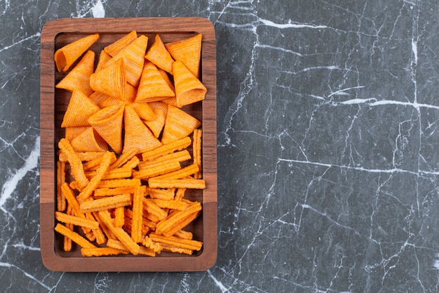 Leckere knusprige Stick- und Dreieckschips auf Holzplatte