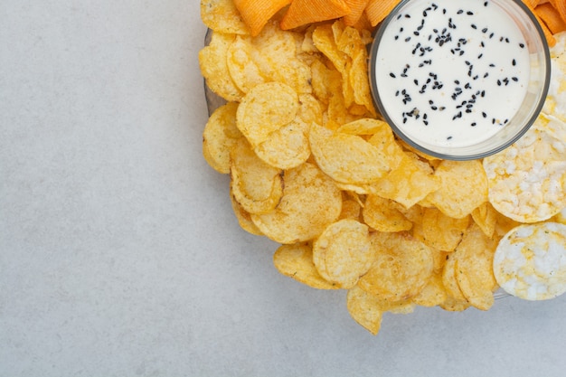 Leckere Kreuzkartoffelchips mit Joghurt auf weißem Hintergrund. Hochwertiges Foto