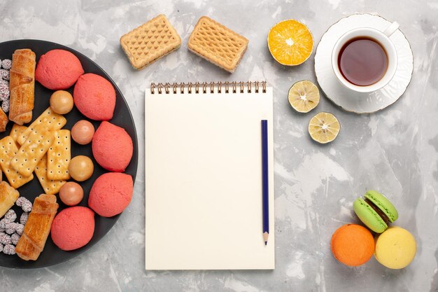 Leckere Kuchen von oben mit Bagels Macarons und Tasse Tee auf grauweißer Oberfläche