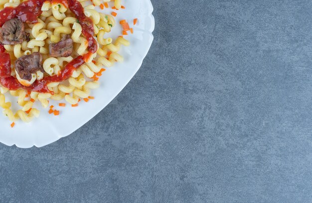 Leckere Pasta mit Fleischstücken auf weißem Teller.