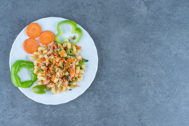 Leckere Pasta mit gehacktem Gemüse auf weißem Teller.