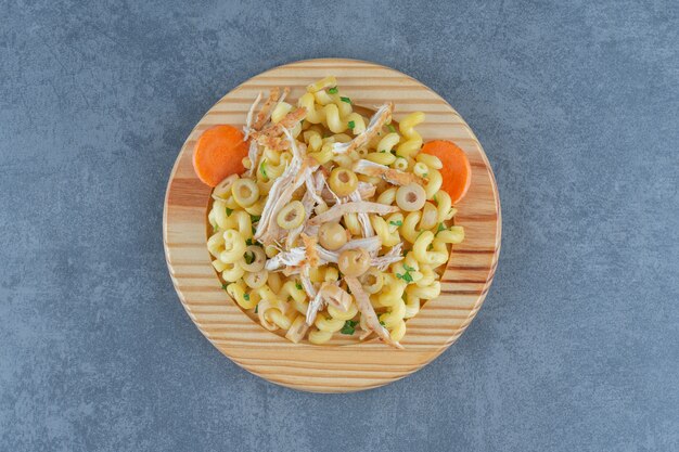 Leckere Pasta mit gehacktem Hühnchen auf Holzplatte.