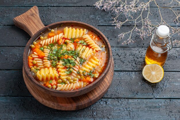 Leckere Pastasuppe mit halber Draufsicht aus spiralförmiger italienischer Pasta mit Grüns auf dunkelblauem Schreibtisch Suppenteller Farbe italienische Pasta-Küche