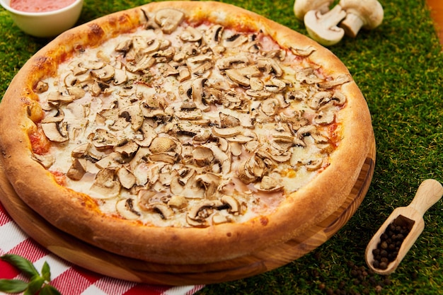 Leckere pizza mit pilzen und summen auf grünem gras | Premium-Foto