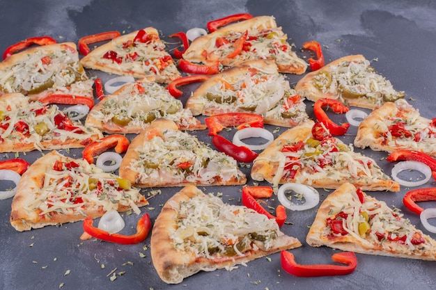 Leckere Pizzastücke auf Blau mit Zwiebelringen und Pfeffer.