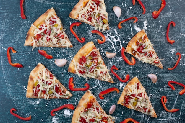 Leckere pizzastücke auf blau mit zwiebelringen und pfeffer.