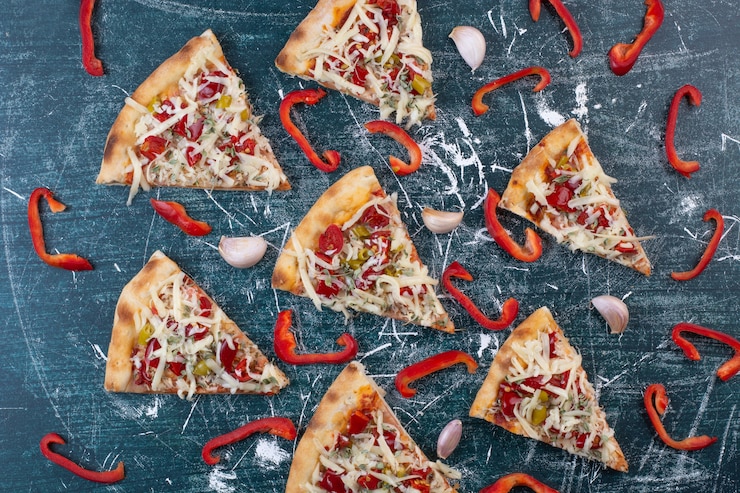Kostenlose Foto leckere pizzastücke auf blau mit zwiebelringen und pfeffer.