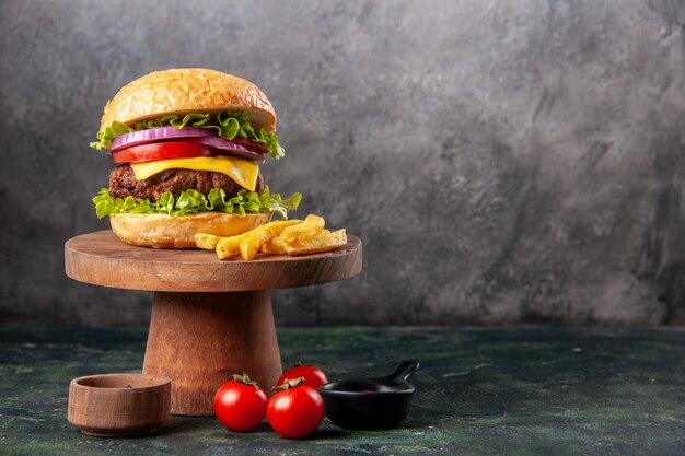 Leckere Sandwich-Pommes auf Holzbrett Tomaten-Ketchup-Pfeffer auf der linken Seite auf dunkler Mischfarboberfläche