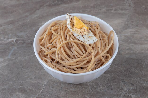 Leckere Spaghetti mit Ei in weißer Schüssel.