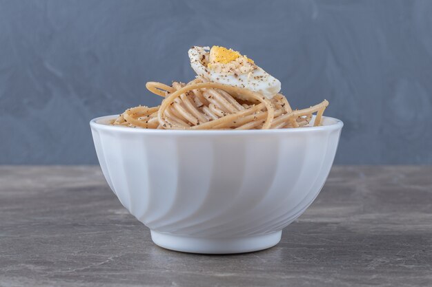 Leckere Spaghetti mit Ei in weißer Schüssel.