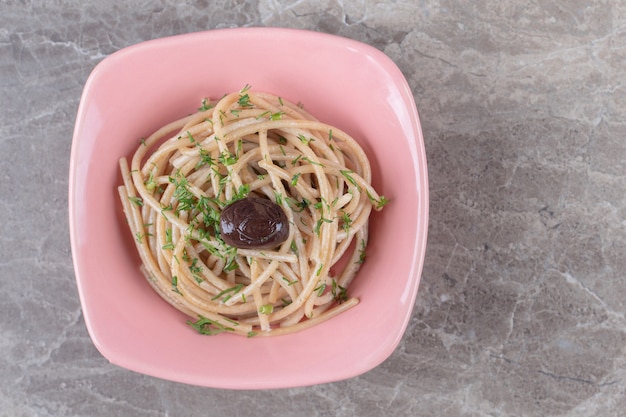 Leckere spaghetti mit grün in rosa schüssel dekoriert.