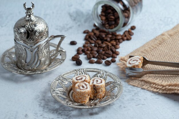 Leckere süße Brötchen, Kaffeebohnen und türkischer Kaffee auf Stein.