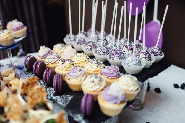 Leckere Süßigkeiten mit violetten und weißen Glasur serviert auf schwarz