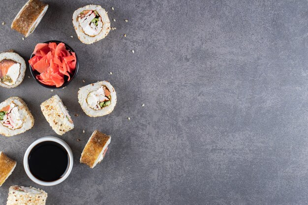 Leckere Sushi-Rollen mit Thunfisch auf Steinhintergrund.