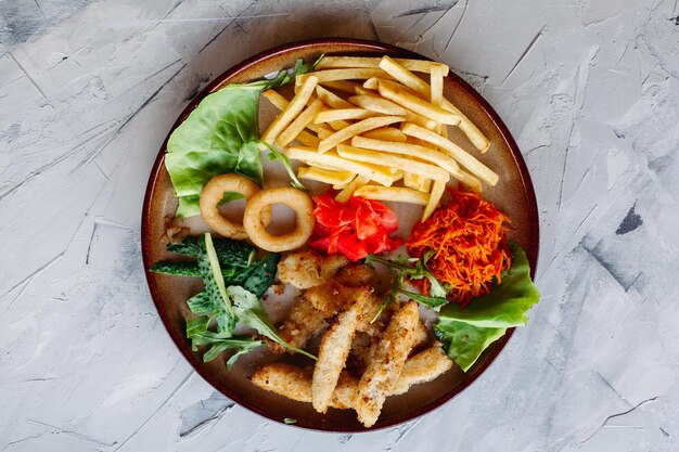 Leckere Vorspeisen im Restaurant für große Unternehmen, darunter goldene Hühnernuggets, Bratkartoffeln, grüne Salatblätter und frische Gurken, die auf einem weißen Tisch stehen und köstlich aussehen