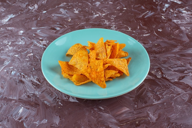 Leckere würzige Chips auf einem Teller auf dem Marmortisch.