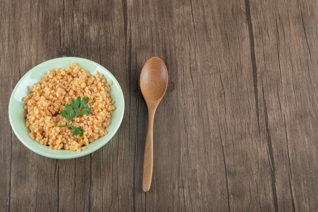 Leckerer Bulgur mit Grüns auf einem grünen Teller