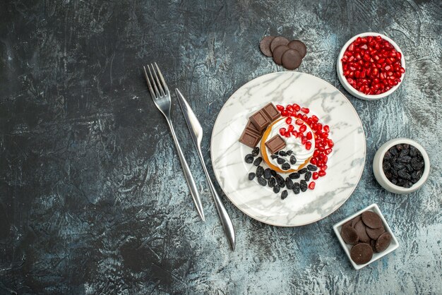 Leckerer cremiger Kuchen der Draufsicht mit Rosinen und Tasse Tee auf hellem dunklem Hintergrund