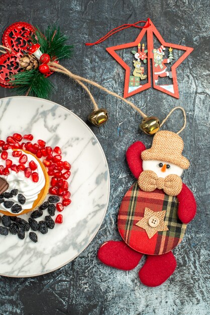 Leckerer cremiger Kuchen der Draufsicht mit Rosinen und Weihnachtsspielzeug auf hellem dunklem Hintergrund
