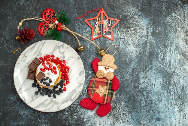 Leckerer cremiger Kuchen der Draufsicht mit Rosinen und Weihnachtsspielzeug auf hellem dunklem Hintergrund