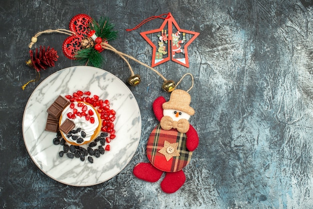 Leckerer cremiger Kuchen der Draufsicht mit Rosinen und Weihnachtsspielzeug auf hellem dunklem Hintergrund