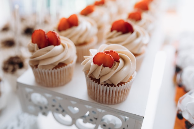 Leckerer Cupcake mit cremigem Belag und Erdbeerscheibe, süßes Buffet