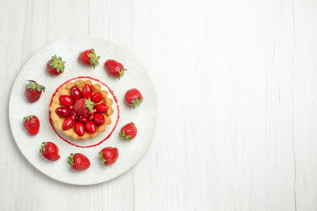 Leckerer Kuchen der Draufsicht mit Früchten innerhalb des Tellers auf dem weißen Schreibtisch