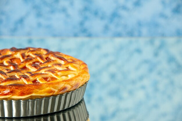 Leckerer Obstkuchen der Vorderansicht innerhalb der Kuchenform auf hellblauem Tisch