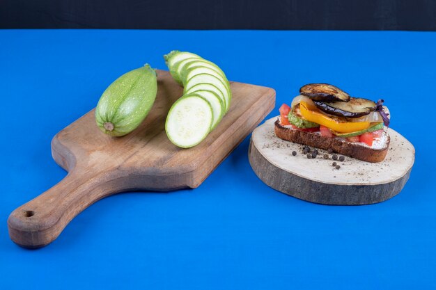 Leckerer Toast mit Gemüse auf Holzstück mit geschnittener Zucchini