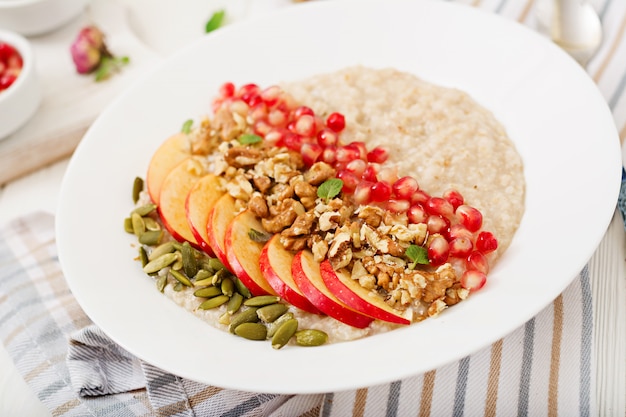 Leckerer und gesunder Haferbrei mit Äpfeln, Granatapfel und Nüssen. Gesundes Frühstück. Fitness Essen. Richtige Ernährung