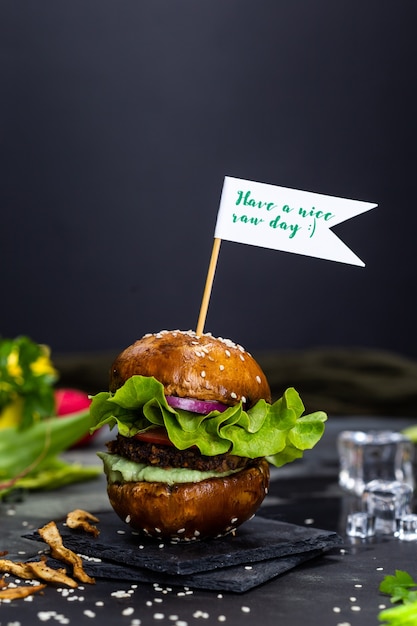 Leckerer veganer Hamburger mit einem Schild "Have a nice raw day" am Stick