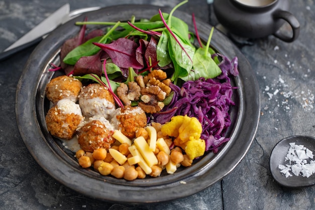 Leckerer veganer vegetarischer Salat mit Kichererbsenfalafel und Blättern auf Teller serviert