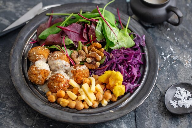 Leckerer veganer vegetarischer Salat mit Kichererbsenfalafel und Blättern auf Teller serviert