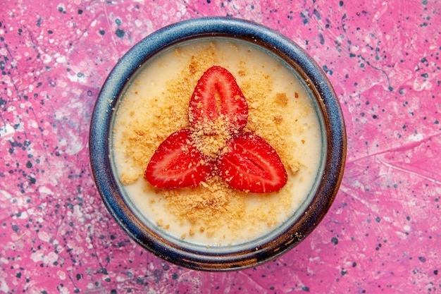 Leckeres cremiges Dessert von oben aus der Nähe mit rot geschnittenen Erdbeeren auf rosa Wanddessert-Eiscreme-Beerenfrüchten