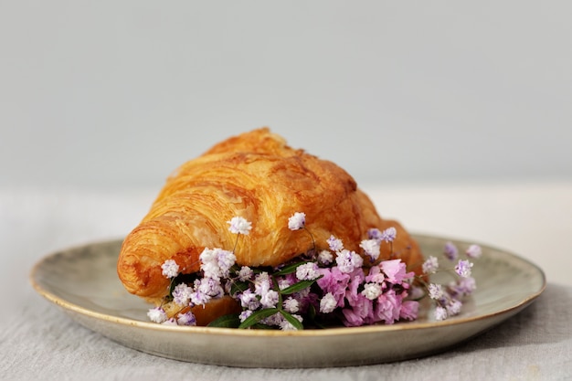 Leckeres Croissant und Blumen auf dem Teller