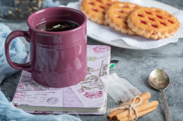 Leckeres Gebäck mit einer Tasse Tee und Zimtstangen.