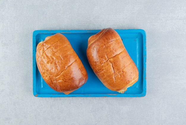 Leckeres Gebäck mit Würstchen auf blauem Brett.