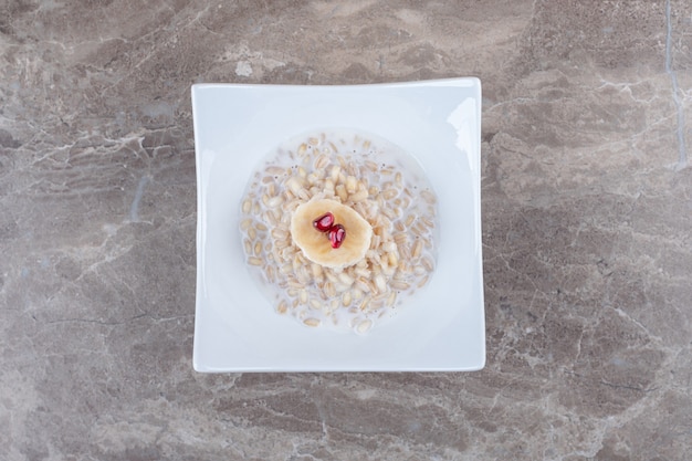 Leckeres granatapfel-aril auf dem zerbrochenen reiskuchen auf der marmoroberfläche