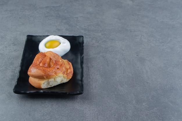 Leckeres hausgemachtes frisches Brötchen auf schwarzem Teller.